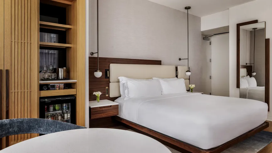 Deluxe King room bedroom with wall-mounted TV and shelving