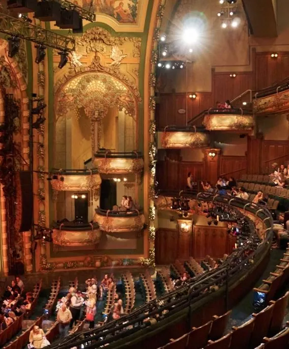 Ornate Broadway theater interior with red seating, night view