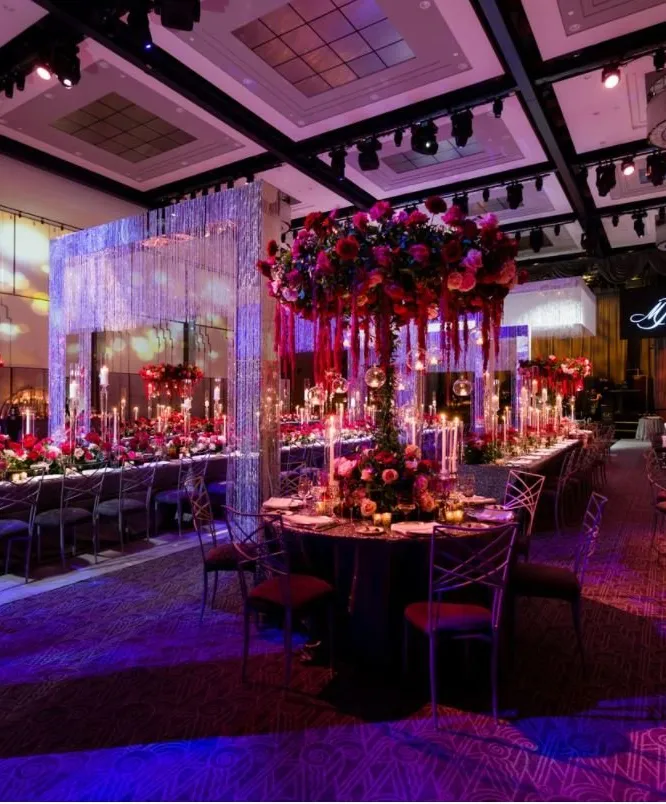 Elegant event venue with red floral arrangements and purple lighting